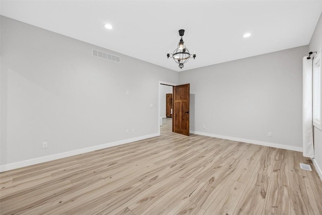 empty room featuring light hardwood / wood-style floors and a notable chandelier