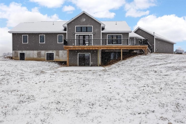 snow covered rear of property with a wooden deck