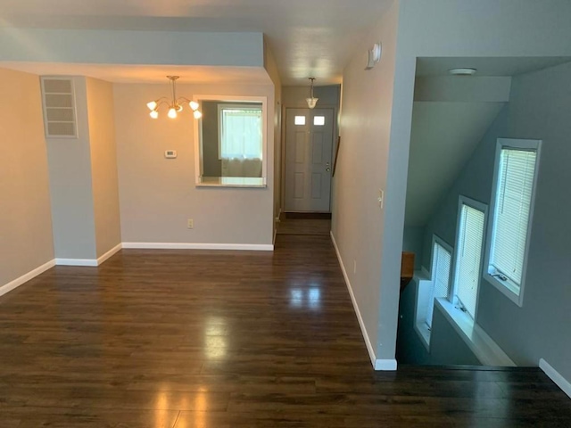 spare room with dark hardwood / wood-style flooring and an inviting chandelier