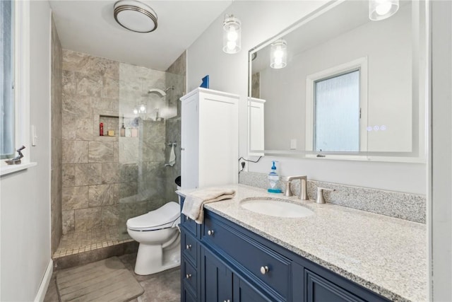 bathroom featuring a tile shower, vanity, and toilet