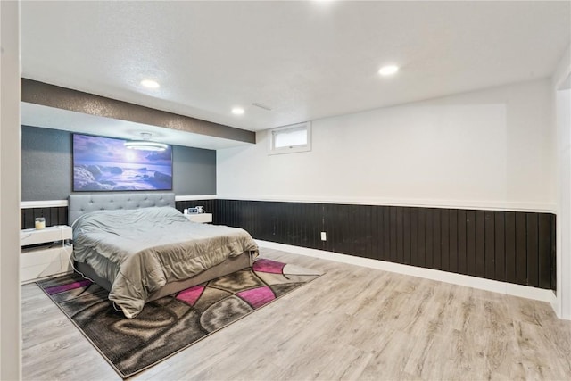 bedroom featuring light wood-type flooring and wooden walls