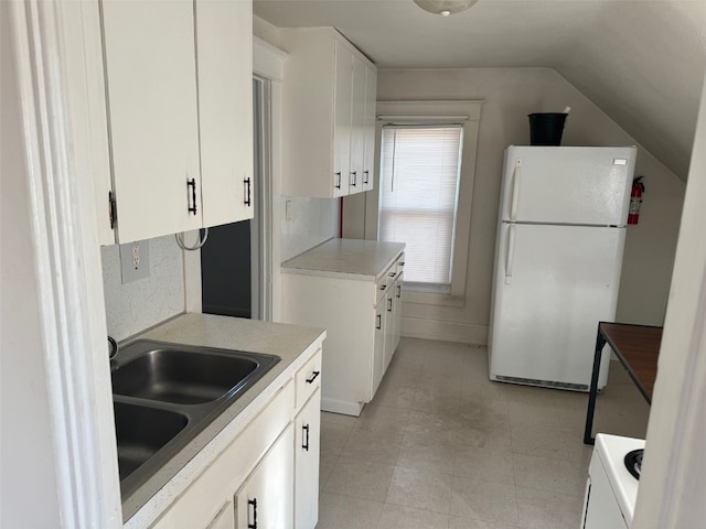 kitchen featuring white cabinets, white refrigerator, lofted ceiling, and sink