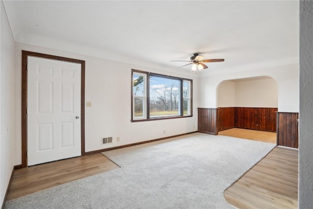 empty room featuring light hardwood / wood-style flooring, ceiling fan, and wood walls