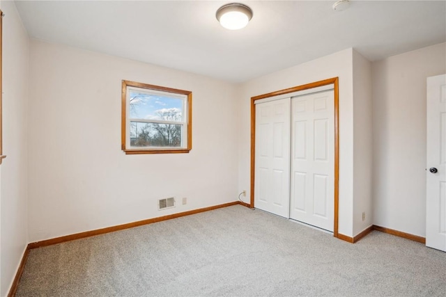 unfurnished bedroom featuring light carpet and a closet