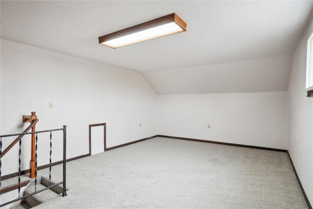 bonus room with light carpet and vaulted ceiling