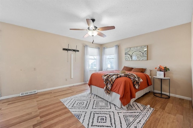 bedroom featuring ceiling fan, a textured ceiling, and light hardwood / wood-style flooring