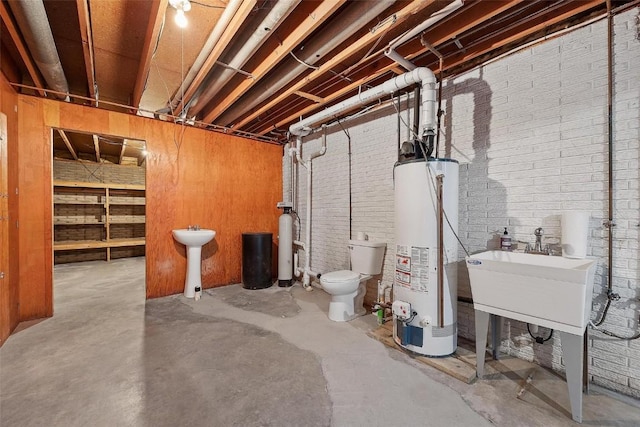 basement with gas water heater, sink, and brick wall