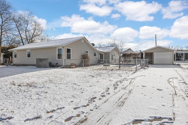 snow covered house with a garage, cooling unit, and an outdoor structure