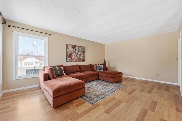 living room with light hardwood / wood-style floors, a textured ceiling, and a wealth of natural light