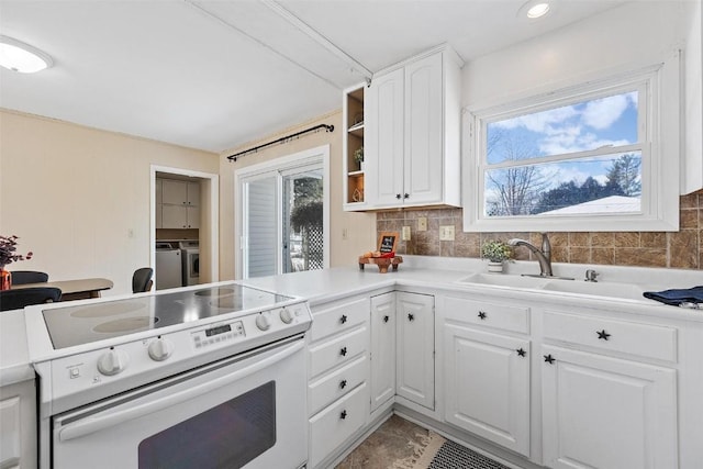 kitchen with backsplash, white cabinets, sink, washing machine and dryer, and white range with electric stovetop