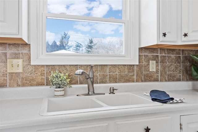 room details featuring backsplash, white cabinetry, and sink