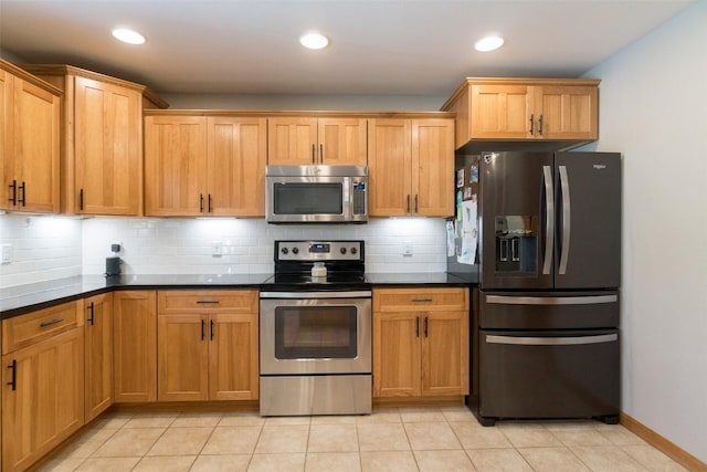 kitchen with backsplash, light tile patterned floors, stainless steel appliances, and dark stone counters