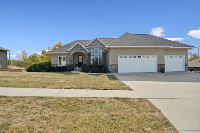 view of front of property featuring a front yard, stone siding, an attached garage, and concrete driveway