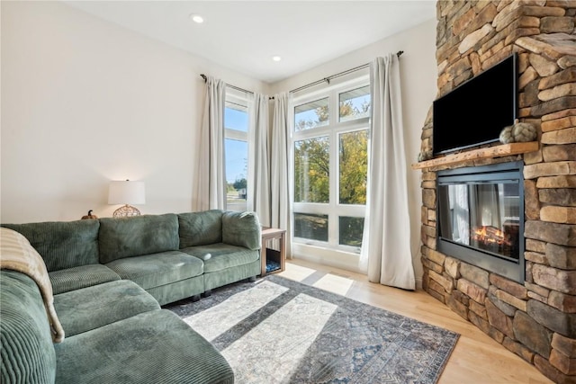 living room with a stone fireplace and light hardwood / wood-style flooring