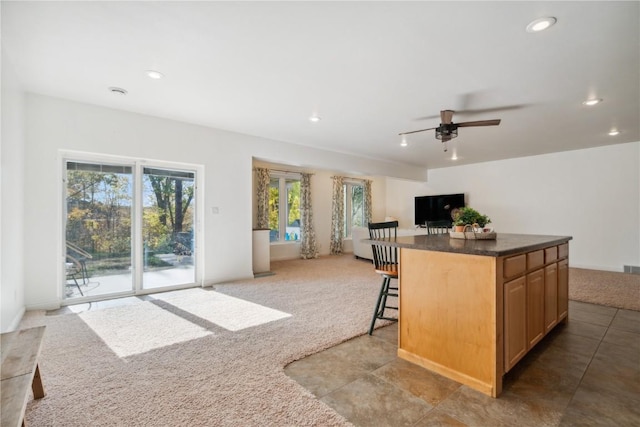 kitchen featuring light carpet, open floor plan, dark countertops, and recessed lighting