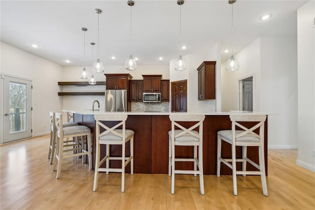 kitchen with open shelves, tasteful backsplash, light countertops, light wood-style flooring, and appliances with stainless steel finishes