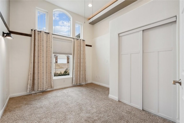 unfurnished bedroom featuring carpet floors, multiple windows, baseboards, and a closet