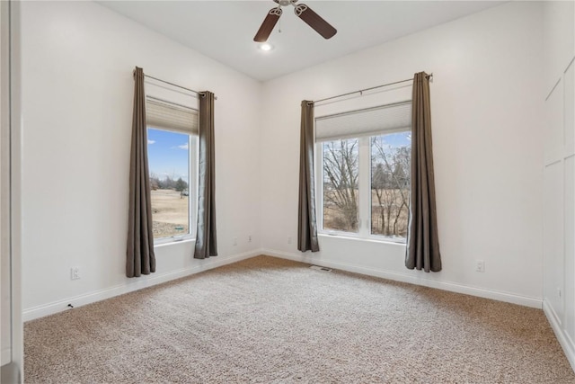 carpeted empty room with visible vents, baseboards, and a ceiling fan