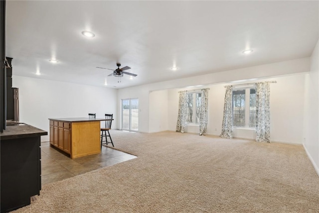 kitchen with recessed lighting, light colored carpet, open floor plan, ceiling fan, and a kitchen bar