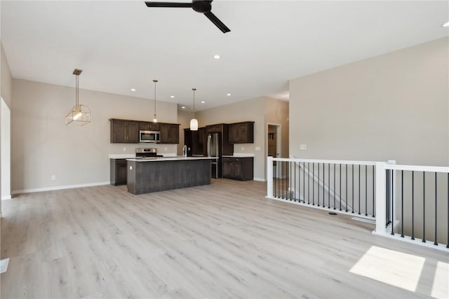 kitchen with ceiling fan, light wood-type flooring, appliances with stainless steel finishes, decorative light fixtures, and a kitchen island