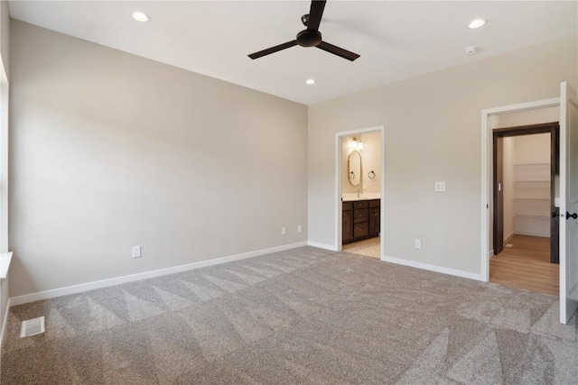 unfurnished bedroom with ceiling fan, light colored carpet, and connected bathroom