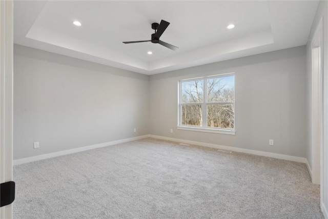 unfurnished room featuring carpet, ceiling fan, and a raised ceiling