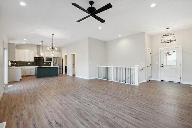 unfurnished living room featuring hardwood / wood-style flooring and ceiling fan with notable chandelier