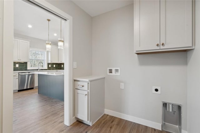 laundry room with sink, cabinets, washer hookup, electric dryer hookup, and light wood-type flooring