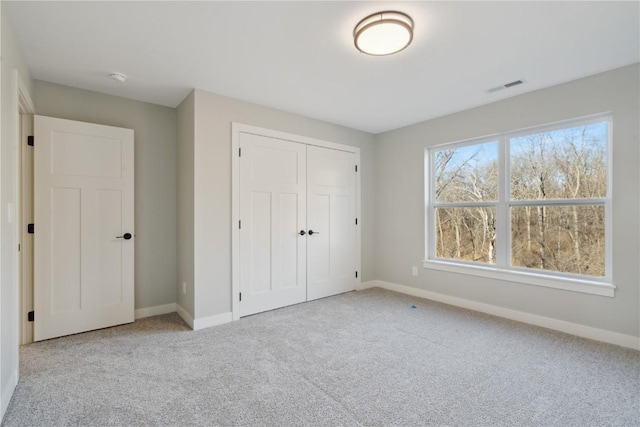 unfurnished bedroom featuring light carpet and a closet