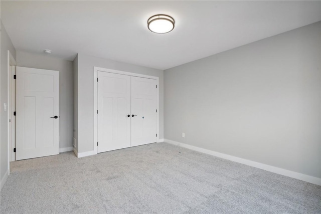 unfurnished bedroom with light colored carpet and a closet