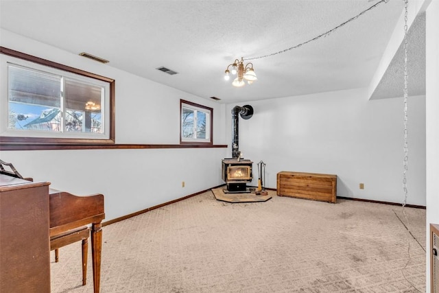 unfurnished room with a wood stove, carpet, visible vents, and baseboards