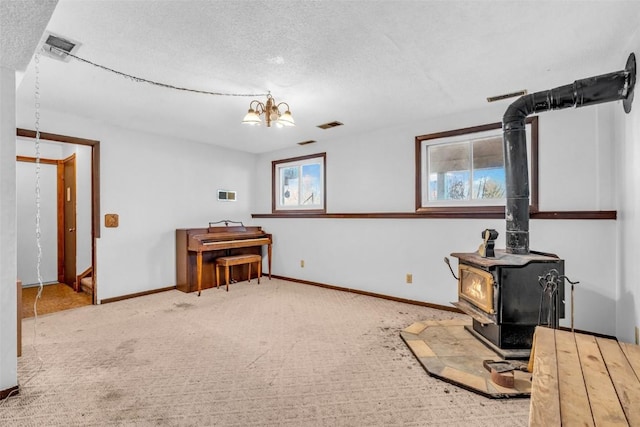 miscellaneous room with a wood stove, an inviting chandelier, visible vents, and a wealth of natural light