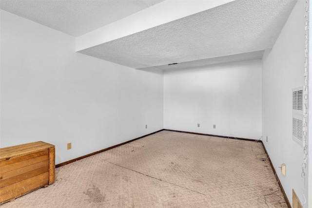 empty room with carpet floors, a textured ceiling, and baseboards