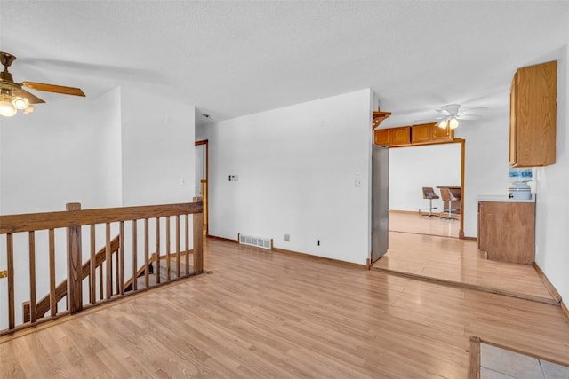 empty room featuring baseboards, visible vents, ceiling fan, and light wood finished floors