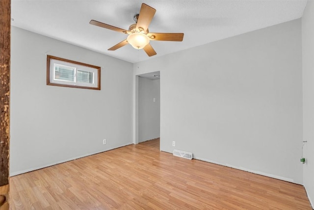 empty room with a ceiling fan, visible vents, and wood finished floors