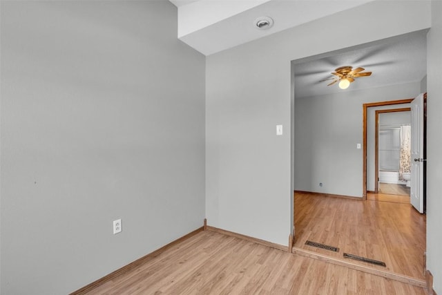 empty room featuring baseboards, light wood-type flooring, visible vents, and a ceiling fan