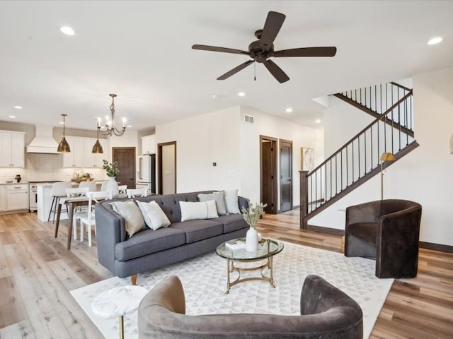 living room featuring light hardwood / wood-style flooring and ceiling fan with notable chandelier