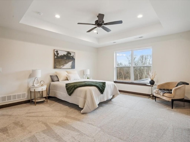 carpeted bedroom featuring a raised ceiling and ceiling fan