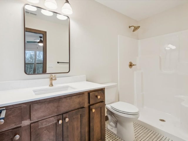 bathroom with a shower, ceiling fan, vanity, and toilet