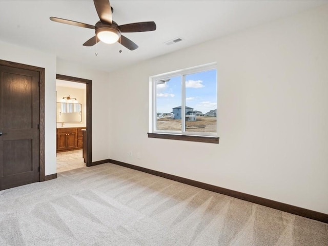 unfurnished bedroom with ensuite bathroom, ceiling fan, and light carpet