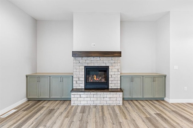 unfurnished living room featuring light wood-type flooring and a brick fireplace