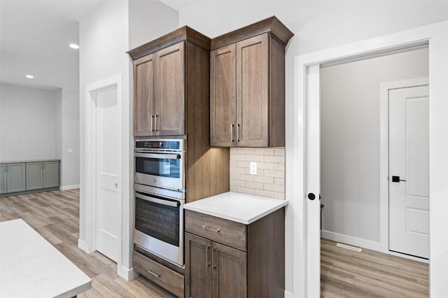 kitchen with decorative backsplash, light hardwood / wood-style floors, and double oven