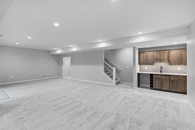 unfurnished living room featuring light colored carpet and sink