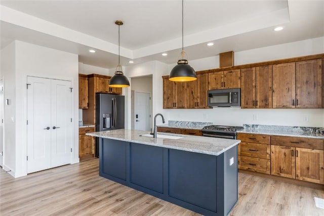 kitchen featuring decorative light fixtures, sink, stainless steel appliances, and a center island with sink