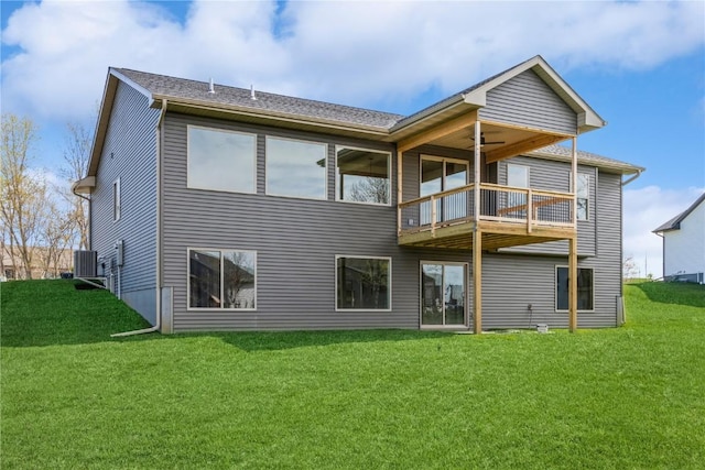 rear view of property with central air condition unit, ceiling fan, a balcony, and a lawn