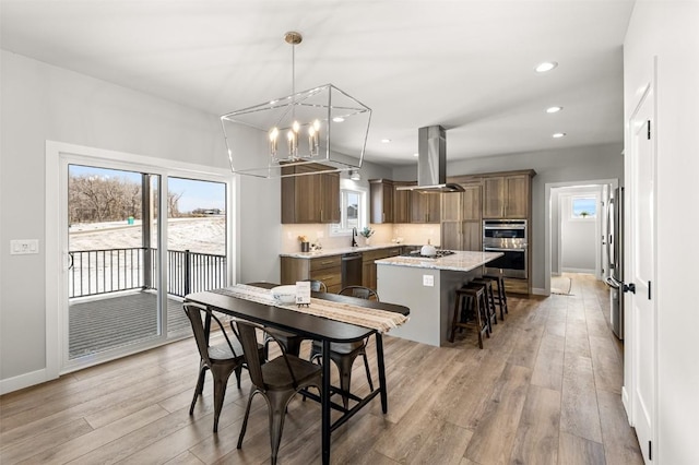 dining area featuring light wood-type flooring, an inviting chandelier, a healthy amount of sunlight, and sink