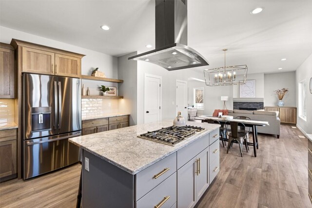 kitchen featuring a center island, hardwood / wood-style flooring, appliances with stainless steel finishes, light stone counters, and island exhaust hood