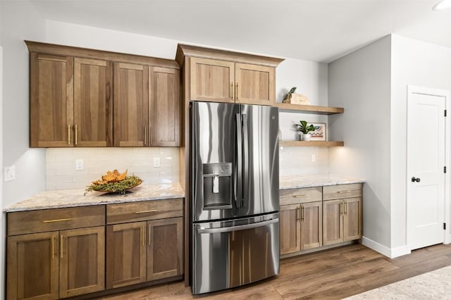 kitchen featuring tasteful backsplash, stainless steel fridge with ice dispenser, dark hardwood / wood-style flooring, and light stone counters