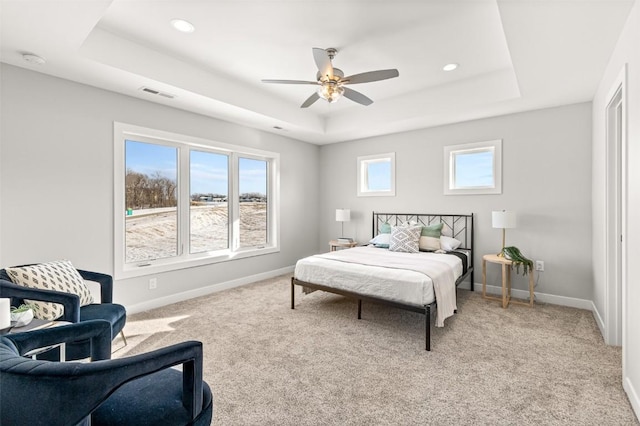 carpeted bedroom featuring ceiling fan and a tray ceiling