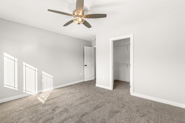 unfurnished bedroom with carpet flooring, a walk in closet, a closet, and ceiling fan